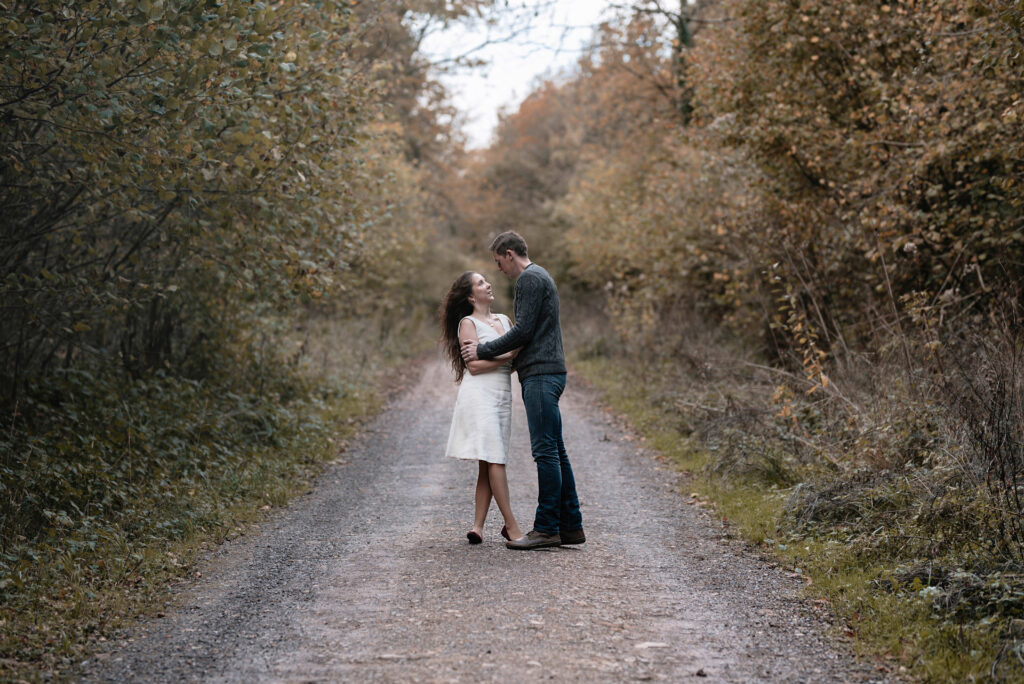 Man catching woman as she spins towards him in a dance motion, in wooded area surrounded by trees