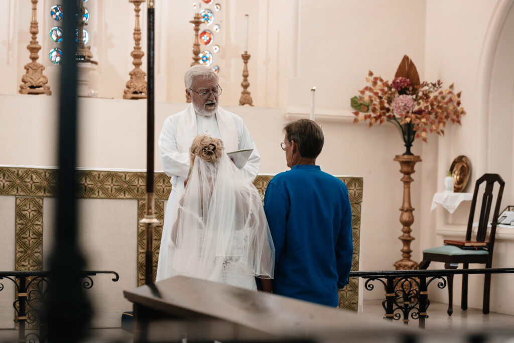 Bride and Groom kneeling before the vicar at the front of the church