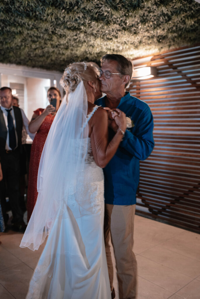 Bride and Groom sharing an intimate first dance at their wedding reception. Friends and family are in the background watching. 