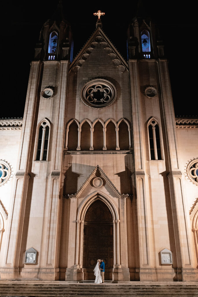 Bride and Groom stood in front of the large front doors of the Parish Church of Our Lady Mount Carmel in St Julian's Malta