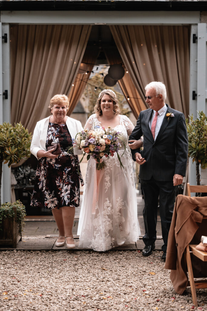 A second wedding photographer capturing the bride walking down the aisle during the ceremony