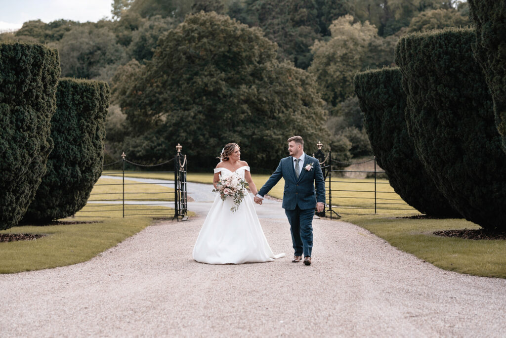 The bride and groom outside of their wedding venue walking hand in hand