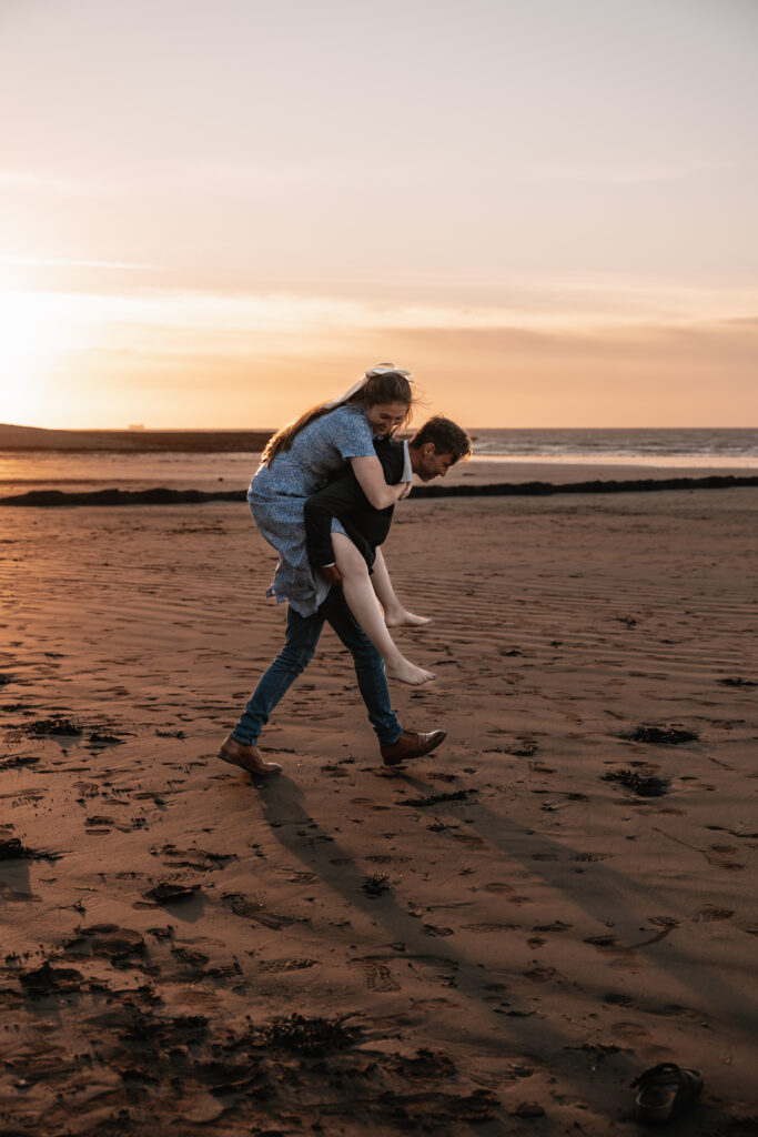 A man giving his partner a piggy back on the beach
