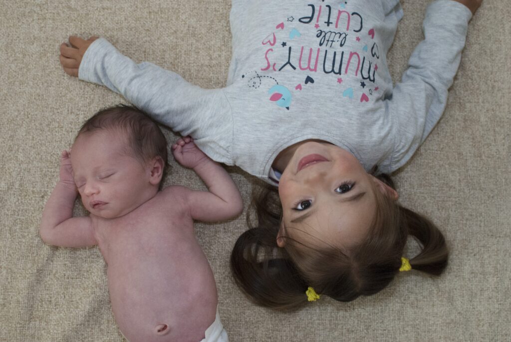 In-home newborn photography of baby sleeping and sibling